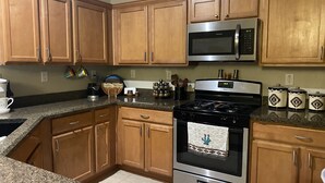 A kitchen with wooden cabinets, a stainless steel stove, a microwave, and granite countertops. - Quit friendly Neighborhood  (Anthem)