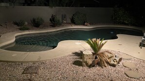 A swimming pool with a curved edge, surrounded by a pebble bed and various plants. - Quit friendly Neighborhood  (Anthem)
