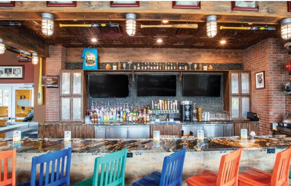 A bar area with a counter, multiple seating options, and a brick wall backdrop.