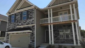 A two-story house with a stone facade, a front porch with columns, and a garage. - ❤️GREAT FOR FAMILIES❤️ (Lawrenceville)