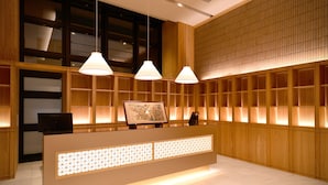 Uma área de recepção com balcão de madeira, luminárias pendentes e uma janela grande.