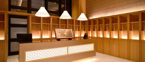 Un área de recepción con un mostrador de madera, lámparas colgantes y un ventanal grande.