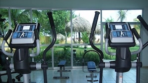 An indoor gym with stationary bikes and exercise equipment, large windows, and a view of a garden. - Luxury Beachfront Condo with Amazing Ocean Views (Gorgona)