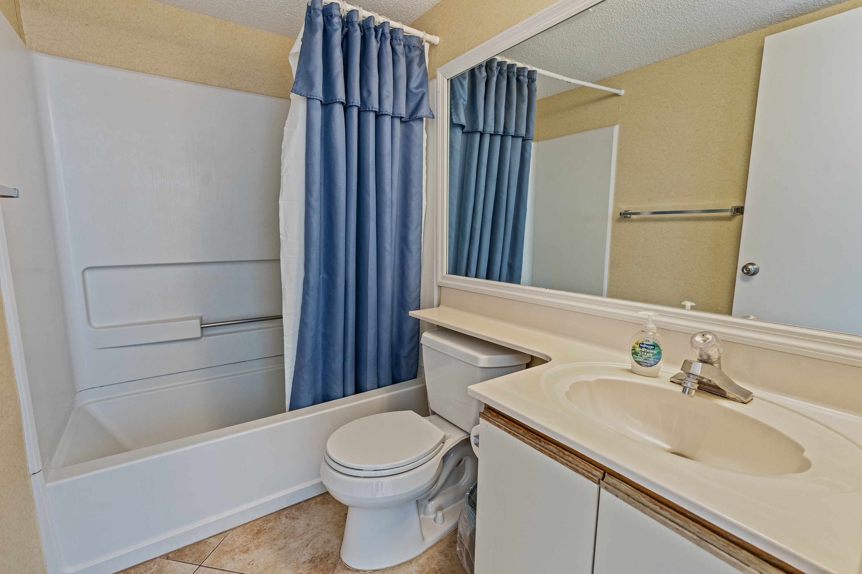 A bathroom with a bathtub, toilet, sink, and a mirror.