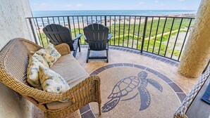 A balcony with wicker furniture, a turtle-themed rug, and a view of the beach. - Sea Castle 2F-Oceanfront 3 Bedroom- Pool & Hot Tub (North Myrtle Beach)