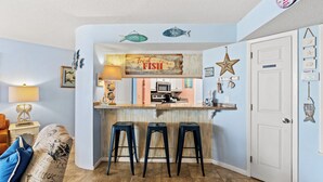 Una cocina con barra, taburetes y decoración de peces en la pared.