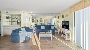 Amplia sala de estar con un conjunto de sofás, una mesa de centro y un televisor.