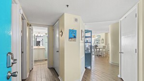 Un pasillo con suelo de madera, paredes color crema y una puerta azul a la izquierda.