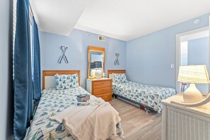 Ein Schlafzimmer mit zwei Betten, einem Schminktisch, einem Spiegel und einer Lampe.