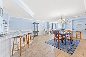 A kitchen with a dining area, a bar, and a large window. - Sea Castle 8B -Updated Oceanfront 3 Bedroom Condo (North Myrtle Beach)