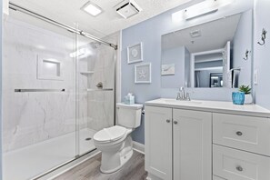 Een moderne badkamer met een douchecabine van glas, een wit toilet en een badkamermeubel met kastjes.