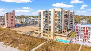 Een hotel met meerdere verdiepingen, balkons, een zwembad en uitzicht op het strand.