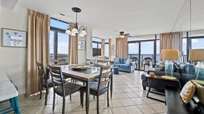 Relax in this inviting living area with a dining table for four, a sofa, and armchair, offering a view of the ocean.