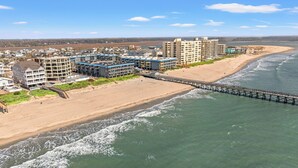 Ein Küstenhotel mit mehreren Gebäuden, einem Steg und einem Strand.