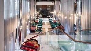 A grand lobby with a grand piano, plush seating, and a glass staircase.