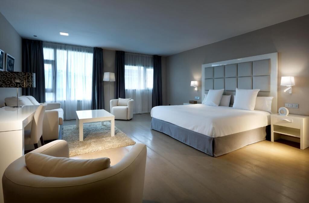 Ein modernes Hotelzimmer mit einem großen Bett, einem Schreibtisch, einem Sessel und einer Couch.
