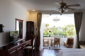 A hotel room with a balcony, a desk with a television, and a bed. - SV Boutique Resort (Ho Chi Minh City)