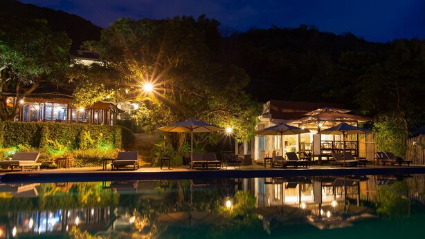 A nighttime resort with a pool, outdoor seating, and illuminated structures. - SV Boutique Resort (Vung Tau)