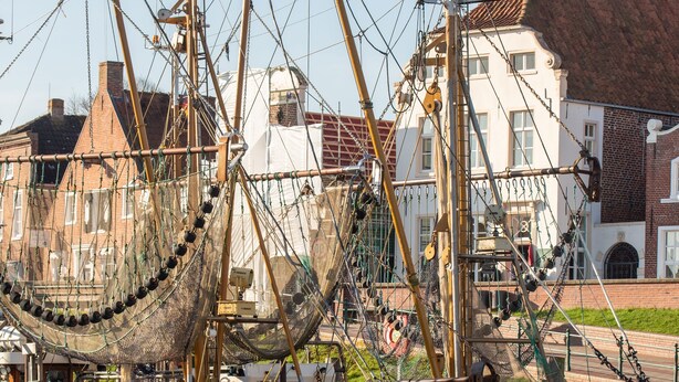 Dos barcos amarrados en un puerto con edificios al fondo.