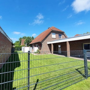 A residential building with a brick exterior, a red-tiled roof, and a fenced yard. - Fantastic,modern holiday apartment"Stüürhuus"in the fishing village of Greetsiel (Krummhörn)