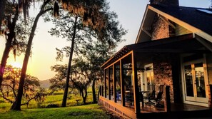 A house with a covered porch, a brick exterior, and a view of a grassy field and trees. - Beautiful Water Views, Huge Yard, Boat Dock, Private, Quiet, Minutes to Beaufort (Beaufort)