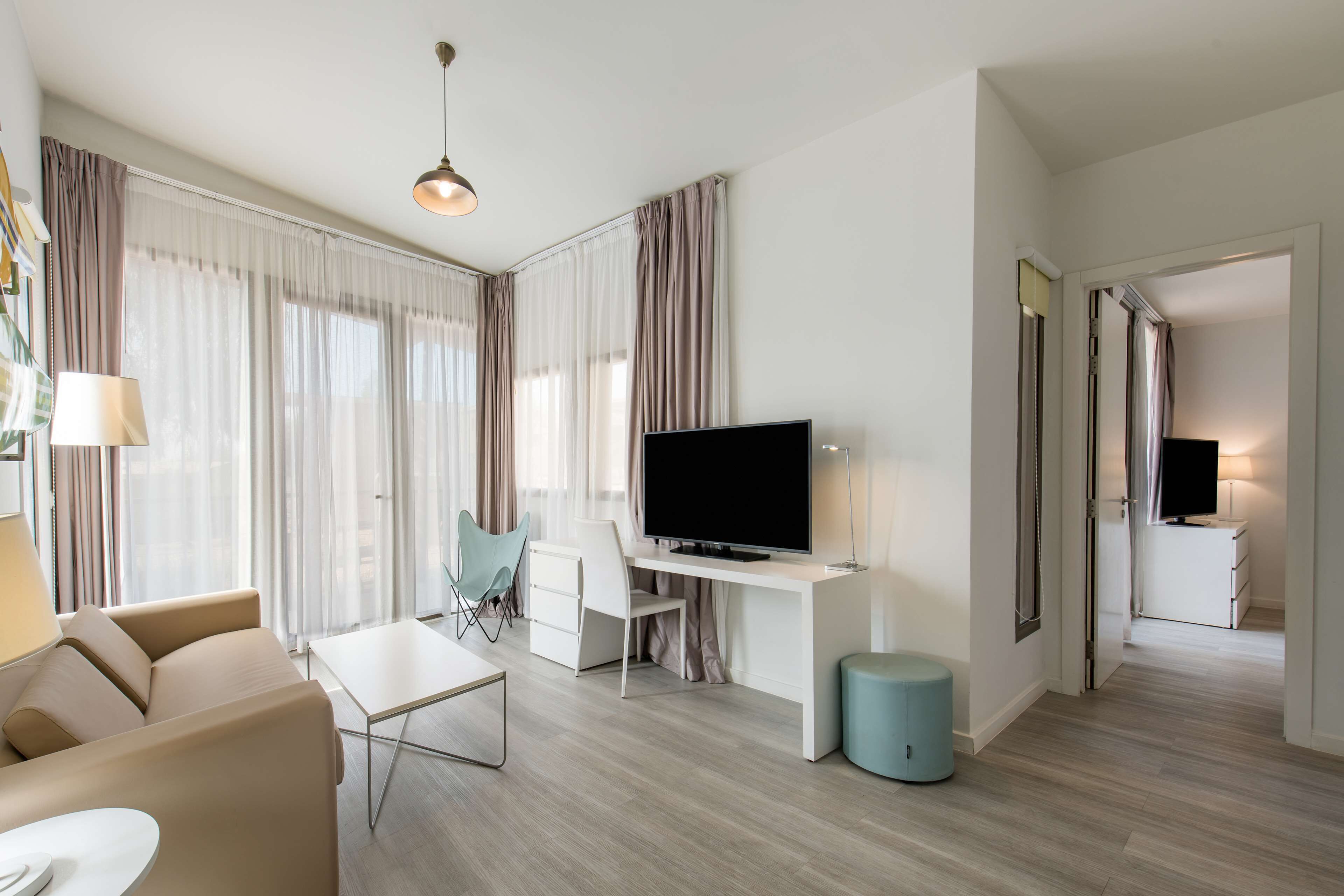 Un salon moderne avec un canapé, une table basse, un téléviseur et un bureau.