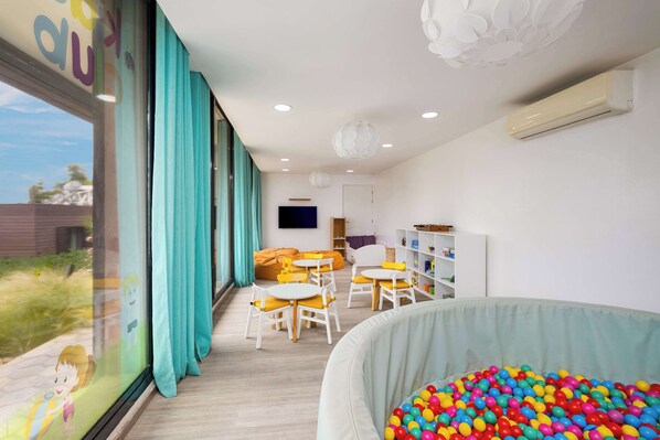 A children's play area with colorful balls, a play table, and chairs.