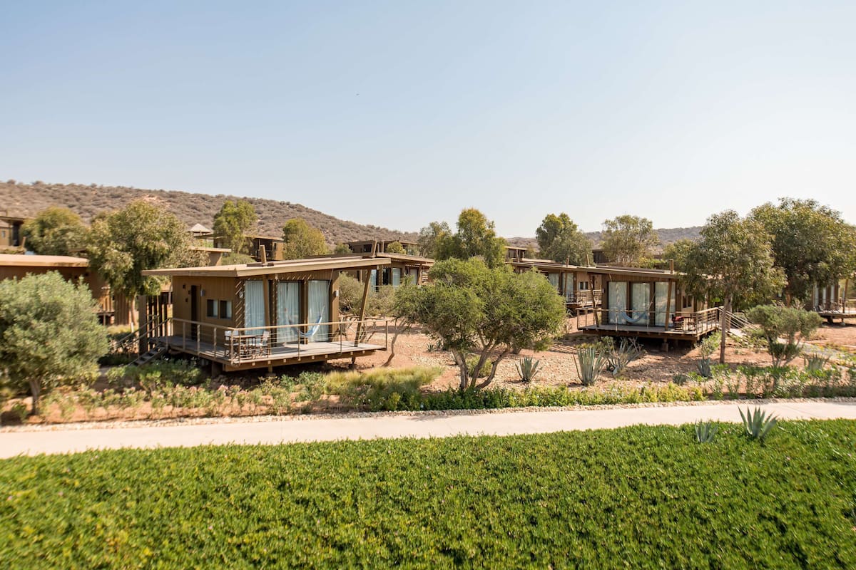 A desert resort with multiple villas featuring balconies, outdoor seating, and a landscaped garden.