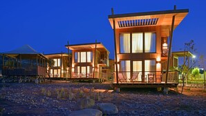 A modern resort with multiple wooden cabins, each featuring large windows and a balcony. - Radisson Blu Resort, Taghazout Bay Surf Village (Taghazout)