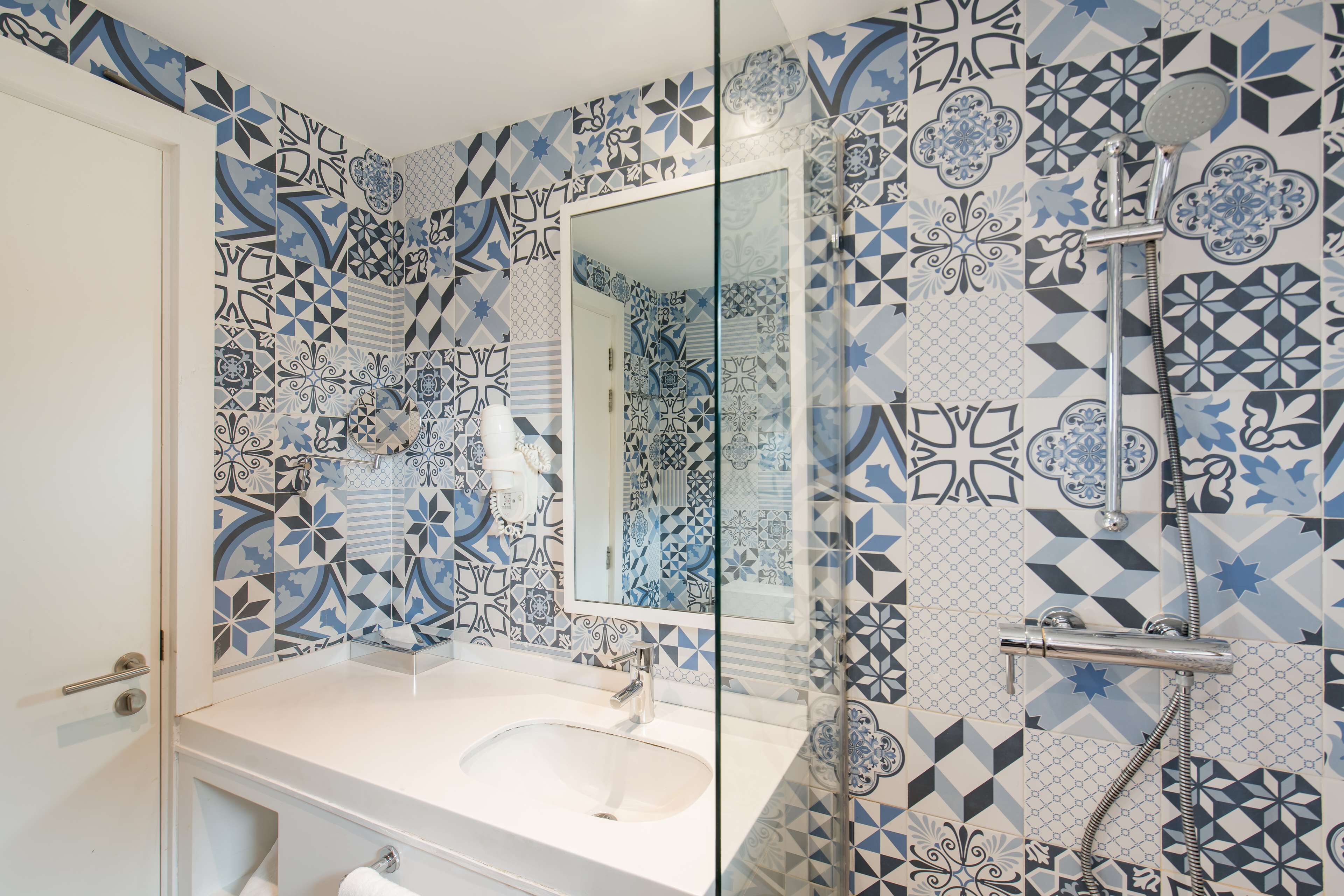 Un baño con un lavamanos blanco, un espejo y una ducha con cabezal de ducha manual.