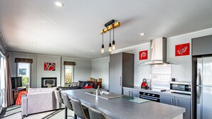 A modern kitchen with a large island, stainless steel appliances, and a seating area with bar stools. - Sunshine and Snow Lodge - Ohakune Holiday Home (Ohakune)