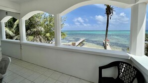 A balcony with a view of the ocean and palm trees. - Belizean Reef Suites (San Pedro)