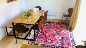 A dining area with a wooden table, four chairs, a laptop, a potted plant, and two paintings on the wall. - Inviting 5-bed House in Eastbourne (Eastbourne)