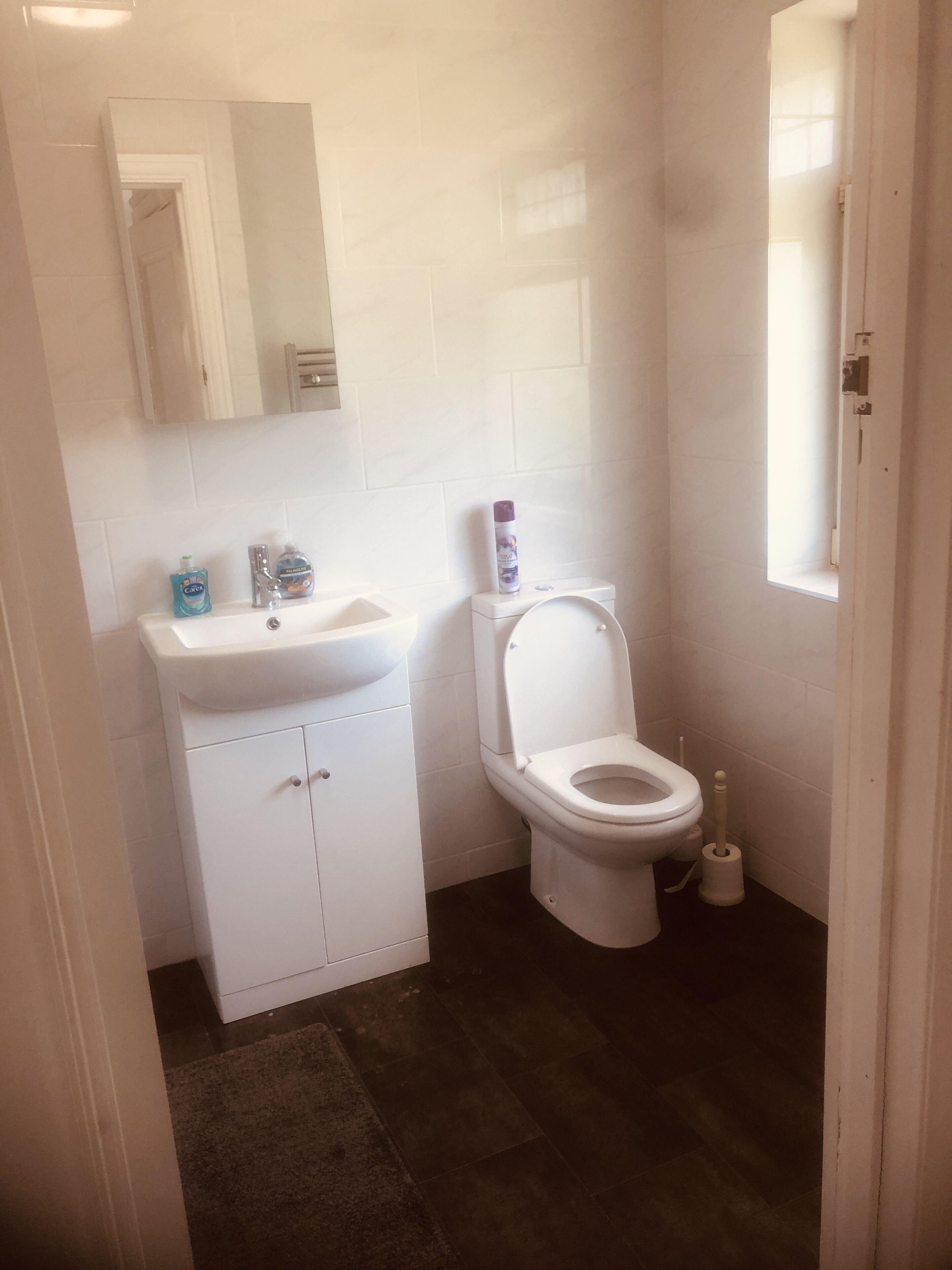 Un baño pequeño y limpio con lavamanos, espejo y retrete blancos.