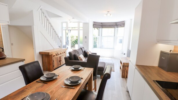 Une cuisine moderne avec un coin repas, des meubles en bois et un escalier menant à un autre niveau.