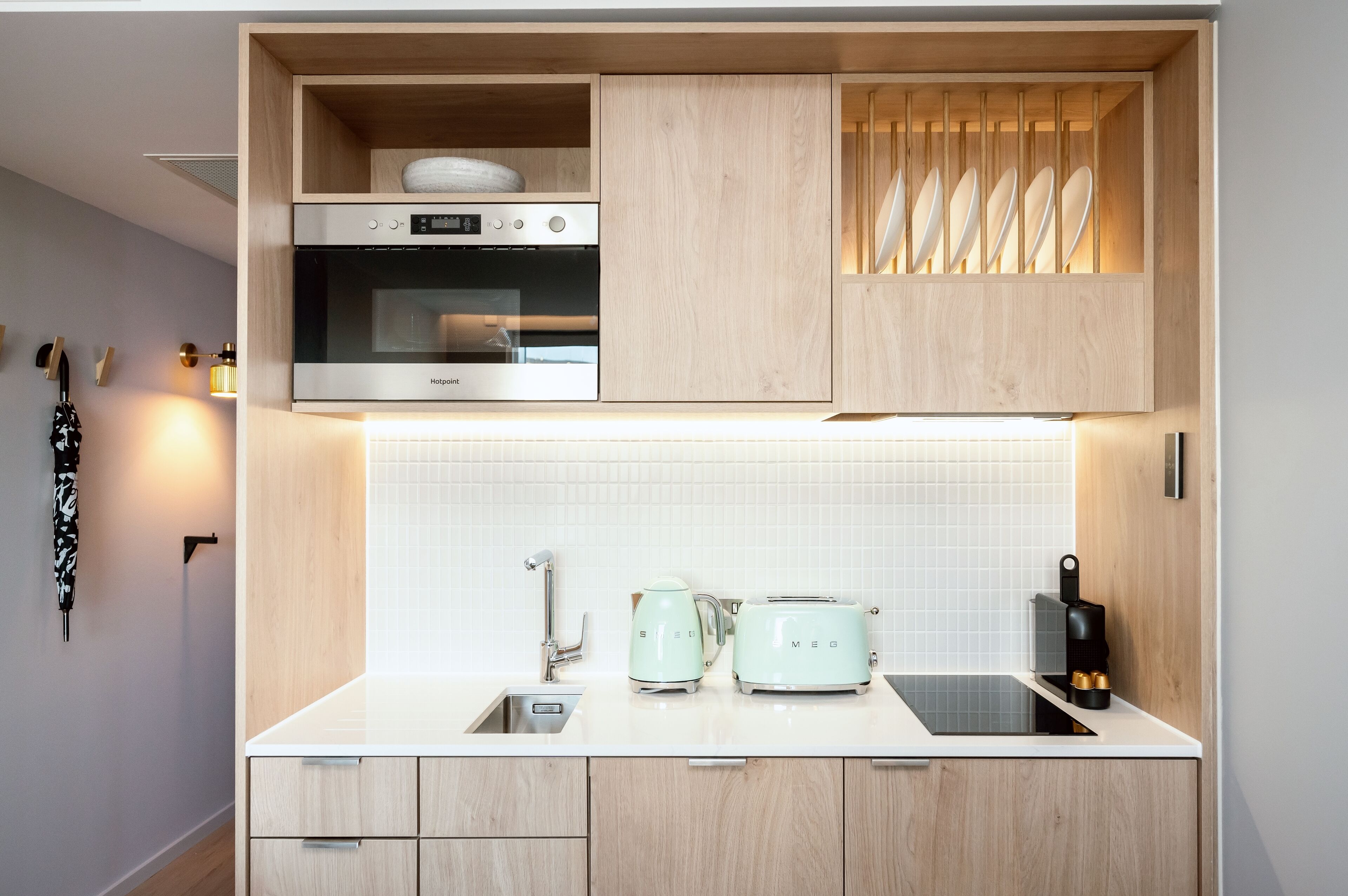 A modern kitchen with a built-in oven, toaster, kettle, and a sink.