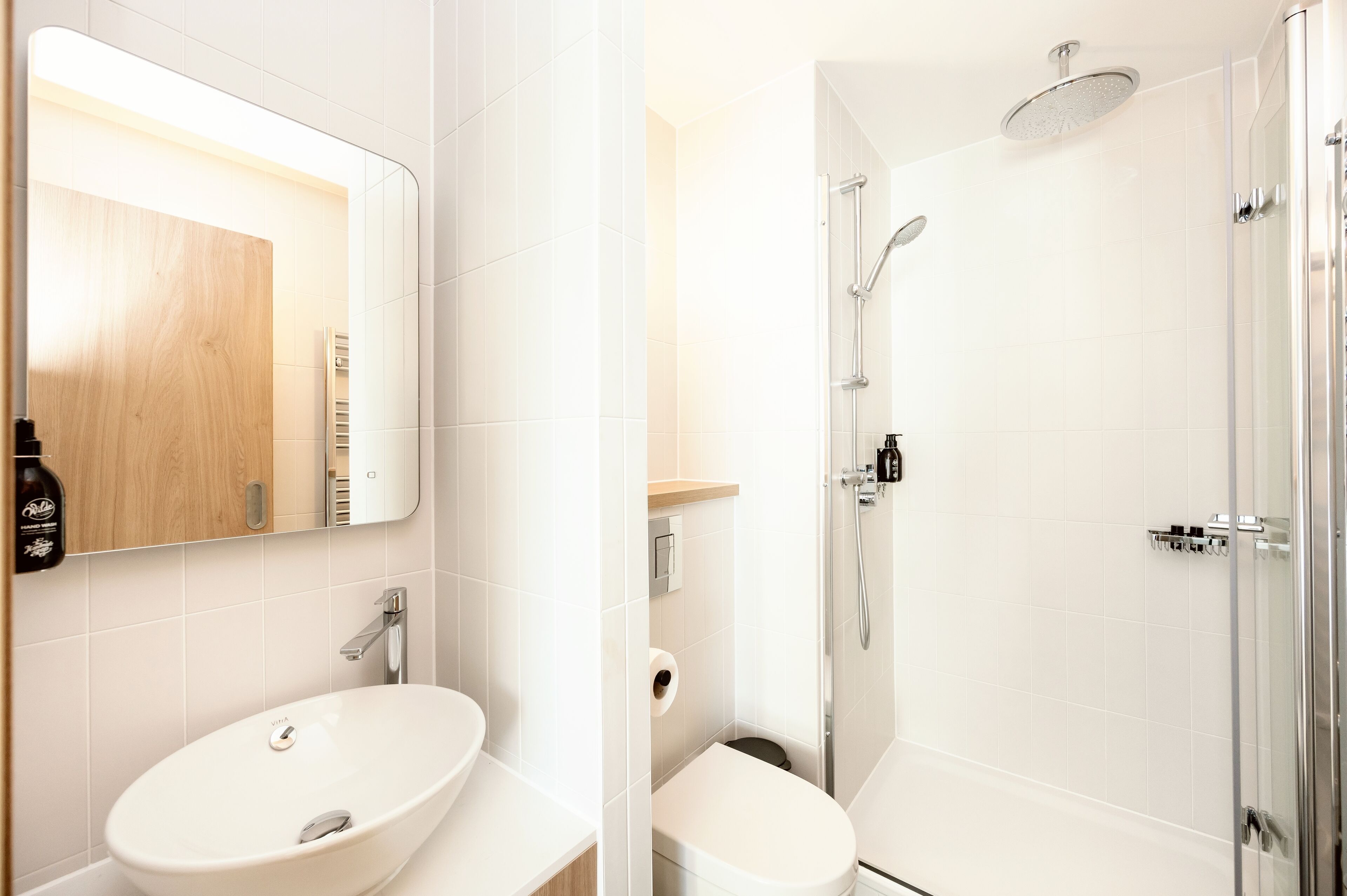 A modern bathroom with a white sink, mirror, and toilet.