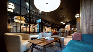 A modern lounge area with seating, a coffee table, and a bar area in the background. - Wilde Aparthotels, London, Paddington (London)