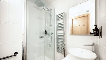A modern bathroom with a glass-enclosed shower, a white sink, and a wooden cabinet.
