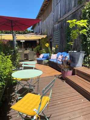 An outdoor patio with a wooden deck, a yellow umbrella, wicker furniture, and potted plants. - Walnut Star Tent @finders Keepers France. Adults Only Retreat. 13 Acres and Lake (Moncrabeau)