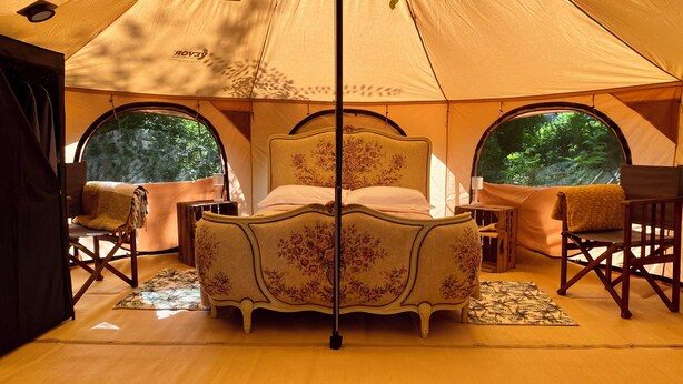 A tent with a bed, two chairs, and a window.