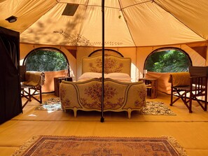 Une tente avec un lit, deux chaises et une fenêtre.