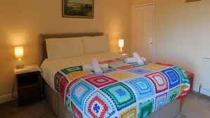 A neatly made bed with a colorful blanket, two bedside lamps, and a painting on the wall. - 7 New Road -  a period, mid terrace house, close to the shops and beach in Sheringham (Sheringham)