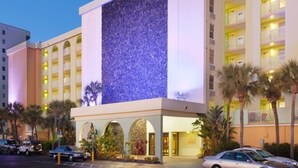 Ein Hotel mit einer großen, beleuchteten Fassade, mehreren Balkonen und einem Parkplatz mit Autos.