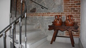 A staircase with a metal railing, a stone wall, and a small wooden table with two pottery items. - Casa Rural de Acogedor Estilo Castellano (Velayos)