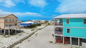 En fastighet vid stranden med flera hus, en sandstrand och en klarblå himmel.