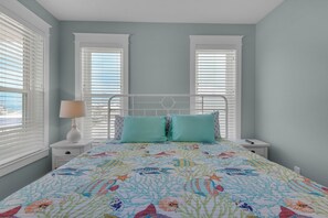 Une chambre à coucher avec un lit, deux tables de chevet, une lampe et une fenêtre avec des stores.