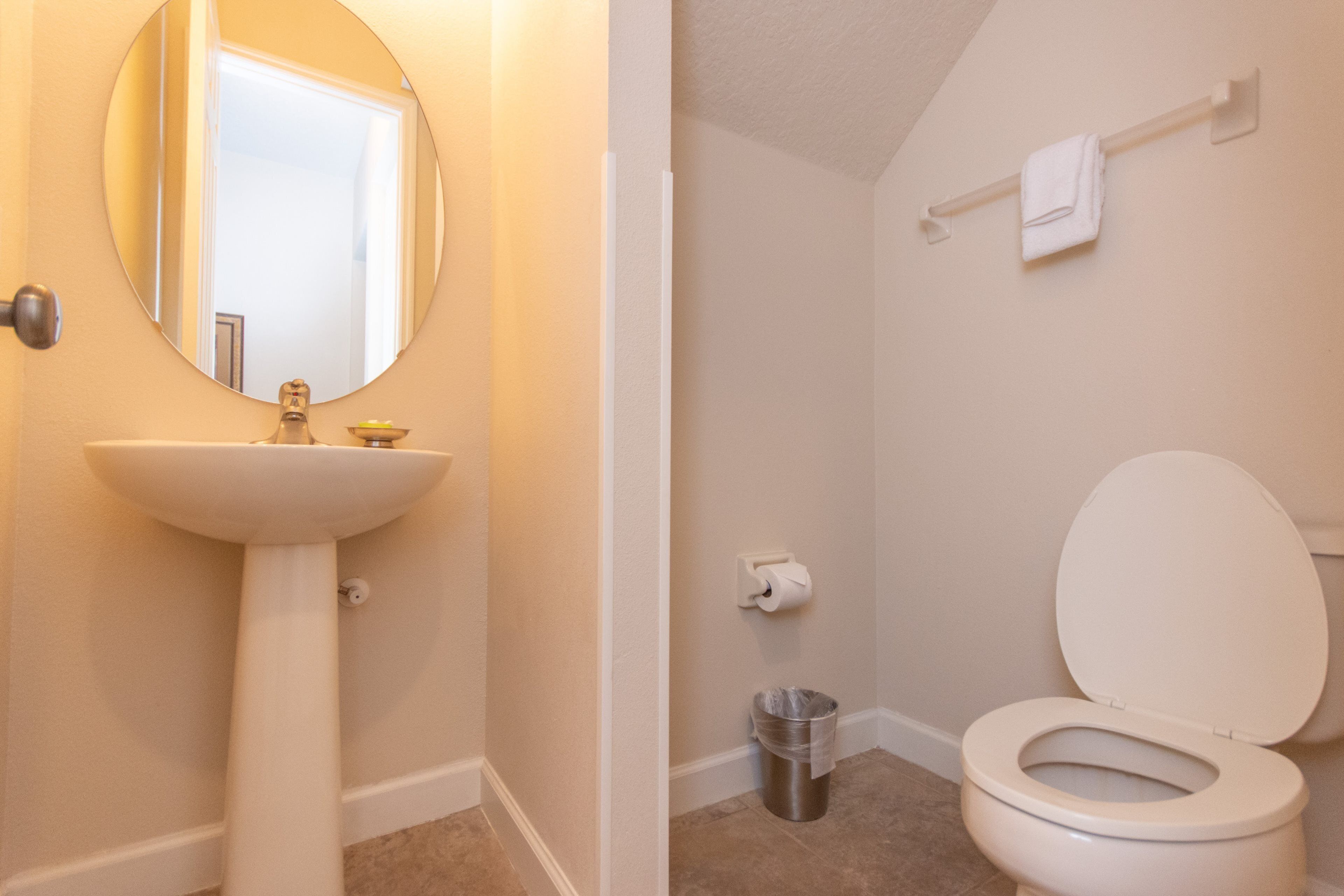 A bathroom with a sink, mirror, toilet, and towel rack.
