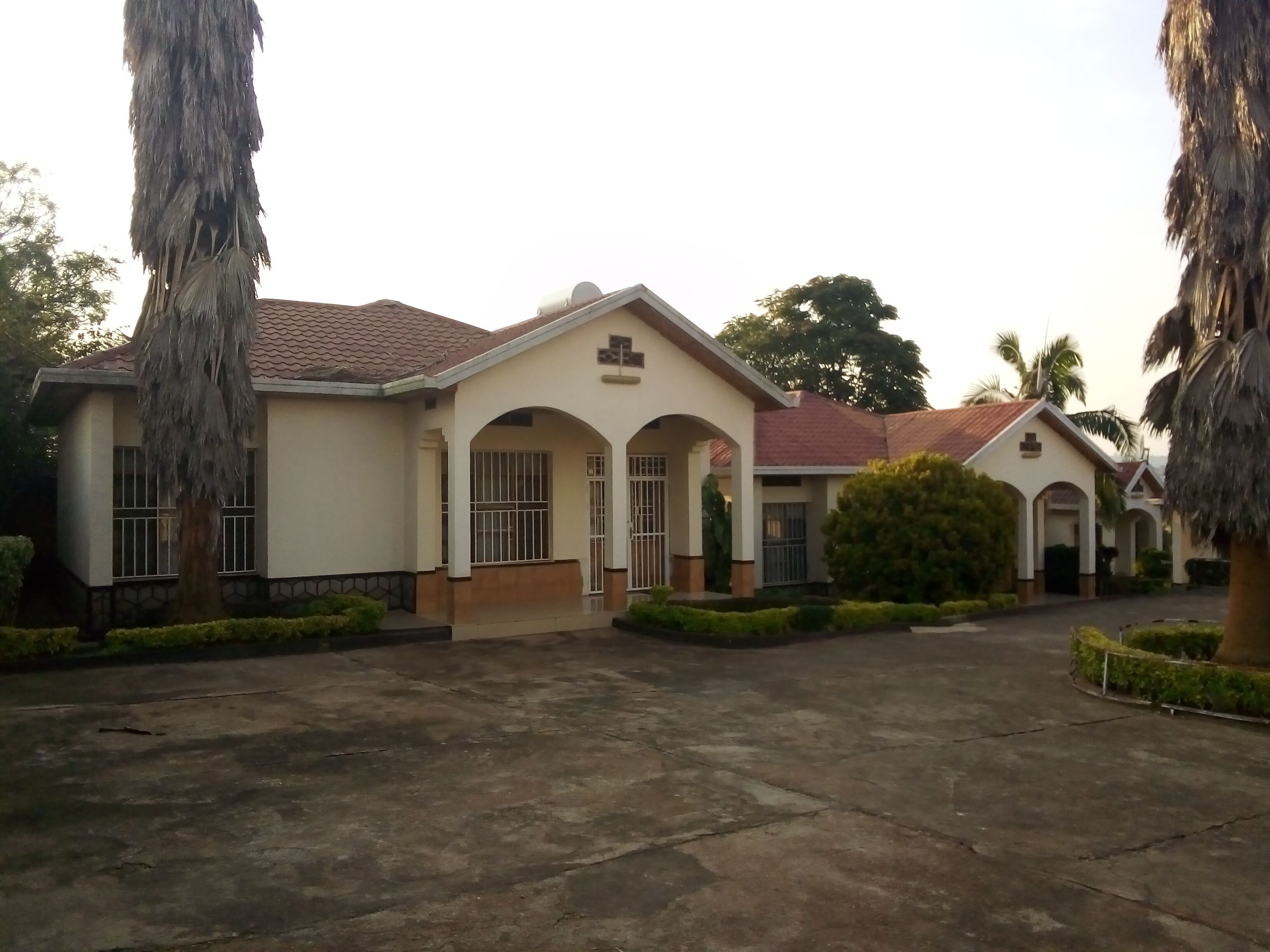 A two-story building with a tiled roof, arched windows, and a central entrance.