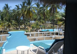 Relax by the resort pool surrounded by lush palm trees and a stunning beach view.